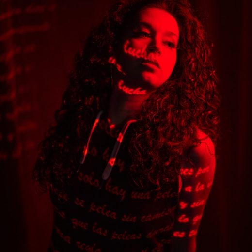 a woman with long curly hair standing in a dark room