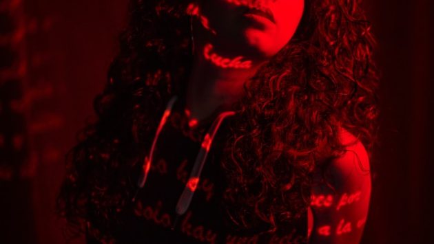 a woman with long curly hair standing in a dark room